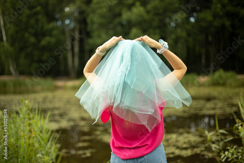Girl in blue cape on her head. Transparent fabric at bridesmaid's. Blue veil on girl.