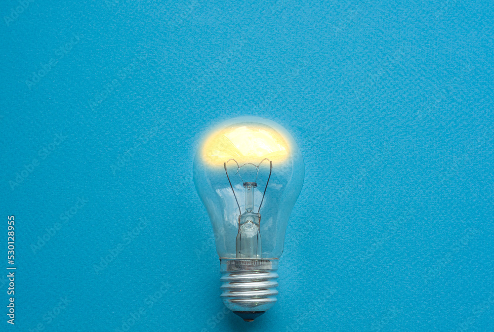 Light bulb isolated turned on in the center of blue background, symbol of idea Light bulb isolated turned on in the center of blue background, symbol of idea