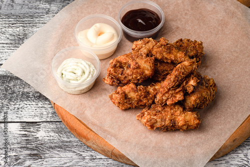 Chicken wings, wings with three sauces on a white wooden background