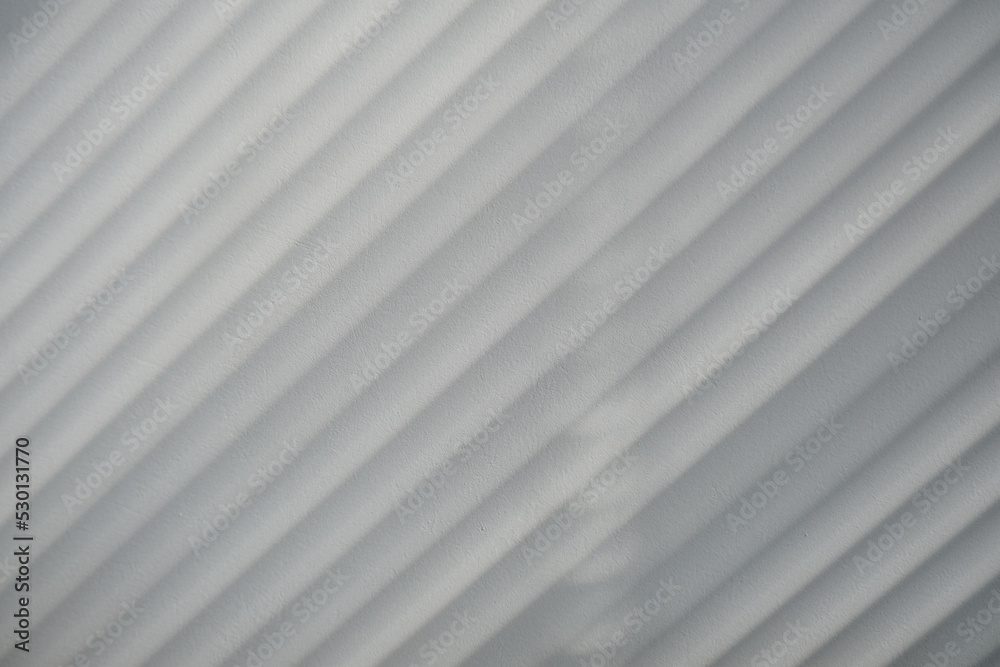 Diagonal blinds shadow on a white plastered wall, black and white style backdrop Diagonal blinds shadow on a white plastered wall, black and white style backdrop