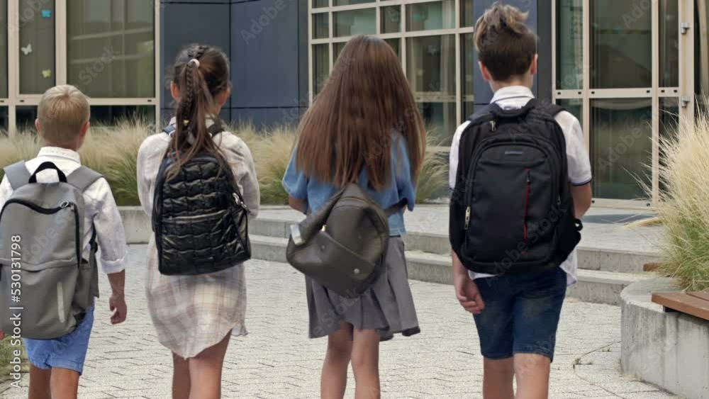 Four first graders, two boys and two girls, approach the school building. Back to school. Four first graders, two boys and two girls, approach the school building. Back to school.
