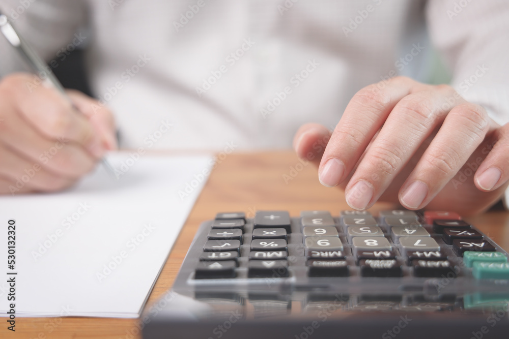 Closeup of businessman hand woking with calculator to calculate the business investment profit, tax and financial status. Business accounting analysis and income report concept. Closeup of businessman hand woking with calculator to calculate the business investment profit, tax and financial status. Business accounting analysis and income report concept.