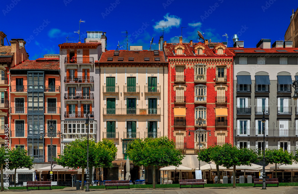 Fototapeta premium Ornate facades of buildings on Historic Plaza del Castillo with restaurants and cafes in Old Town Pamplona, Spain famous for running of the bulls