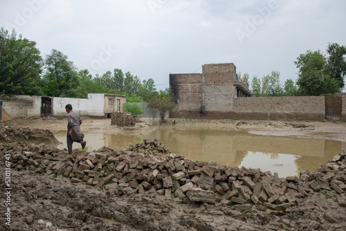 the ruins of the city after flash flood in Pakistan, children tread around the heavy mud photo