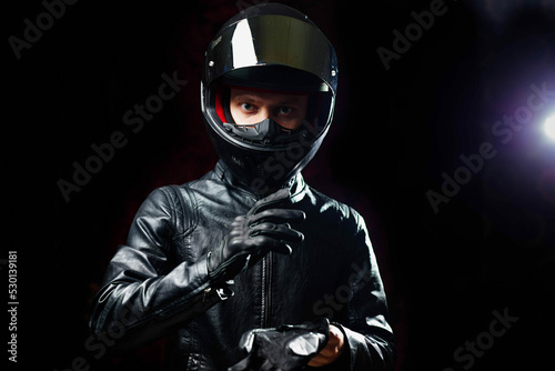 man in a motorcycle helmet in an outfit on a dark studio background.