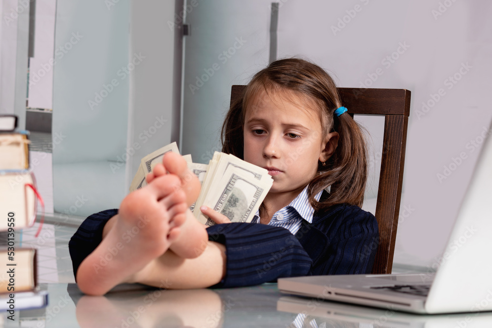 Close up humorous portrait of happy cute young business girl counts money profit with bare feet on the table. Selective focus on eyes of girl. Close up humorous portrait of happy cute young business girl counts money profit with bare feet on the table. Selective focus on eyes of girl.