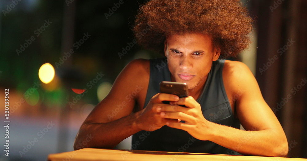 Upset african man looking at cellphone with surprise and disbelief candid Upset african man looking at cellphone with surprise and disbelief candid
