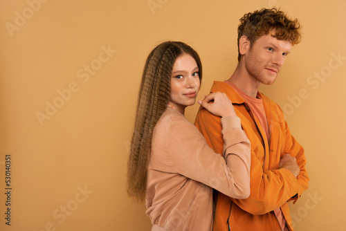 teenage girl with wavy hair hugging redhead boyfriend isolated on beige. © LIGHTFIELD STUDIOS