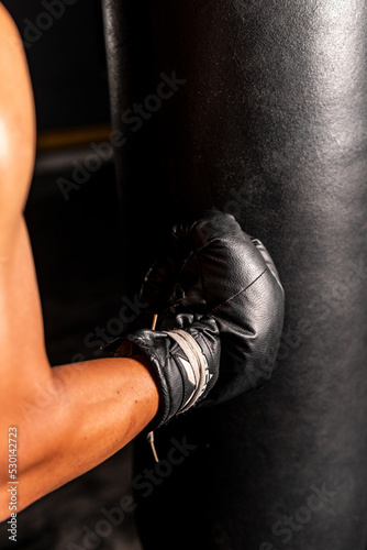High quality photography. Close up of a man's hand with a boxing glove hitting the bag. Boxing scene.