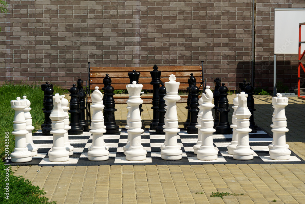 Outdoor chess board with big plastic pieces. Outdoor giant chess. Leisure and activities.