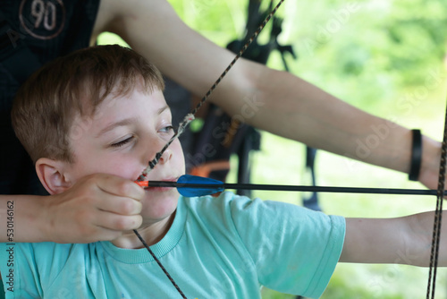 Instructor teaches child how to shoot bow