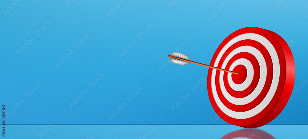 Target success concept, red dartboard and arrow with copy space on blue wall background Target success concept, red dartboard and arrow with copy space on blue wall background