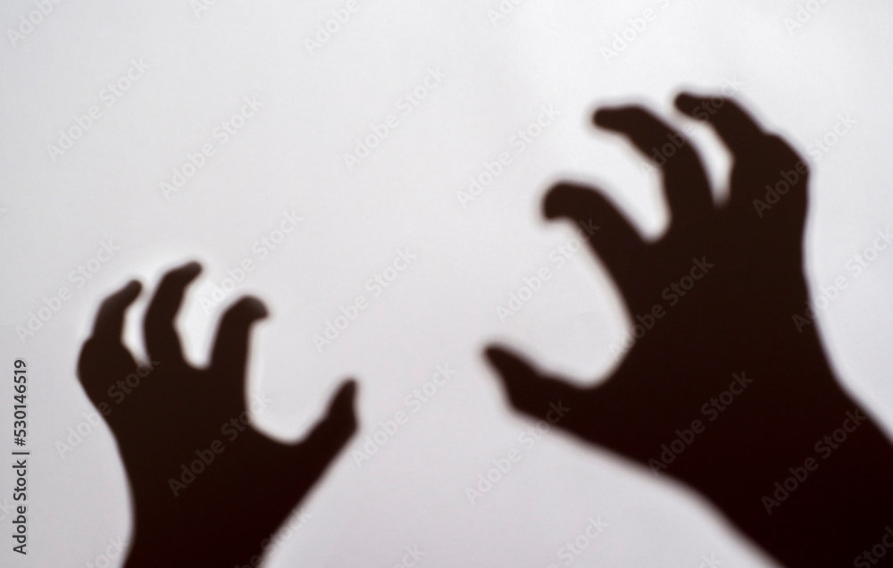 The shadow of a crooked hand on a light background. Horror Concept, Halloween.