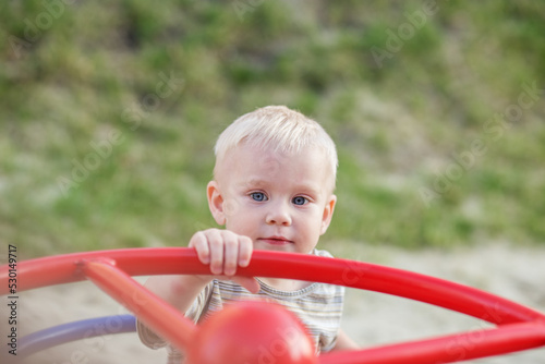 Little boy rides on carousel swing. Toddler plays on playground in summer. Concept of kindergarten
