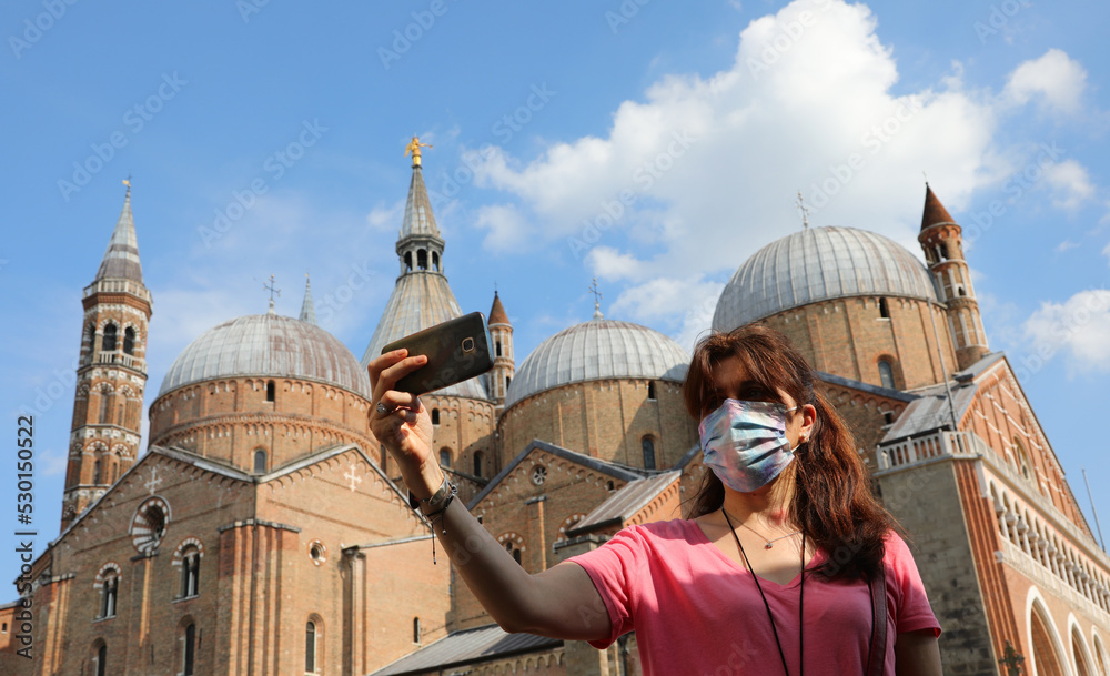 Φωτογραφία young woman with surgical mask taking a photo with smartphone in Padua and the B