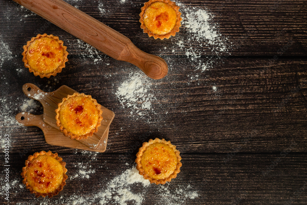 Artisanal tarts with caramelized tops sit amidst a flour-dusted backdrop, accompanied by a traditional rolling pin, ready for a sweet indulgence Artisanal tarts with caramelized tops sit amidst a flour-dusted backdrop, accompanied by a traditional rolling pin, ready for a sweet indulgence