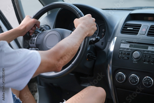 Male hands on the steering wheel of a car 