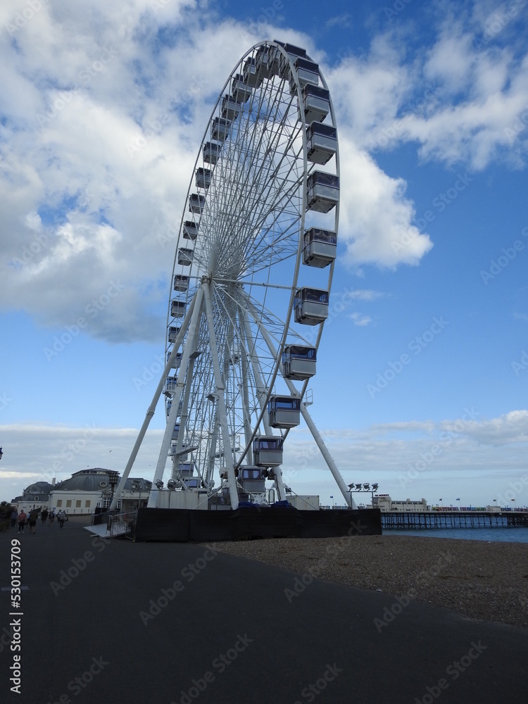 A large viewing wheel on the sea beach close to the promenade overlooking the pier