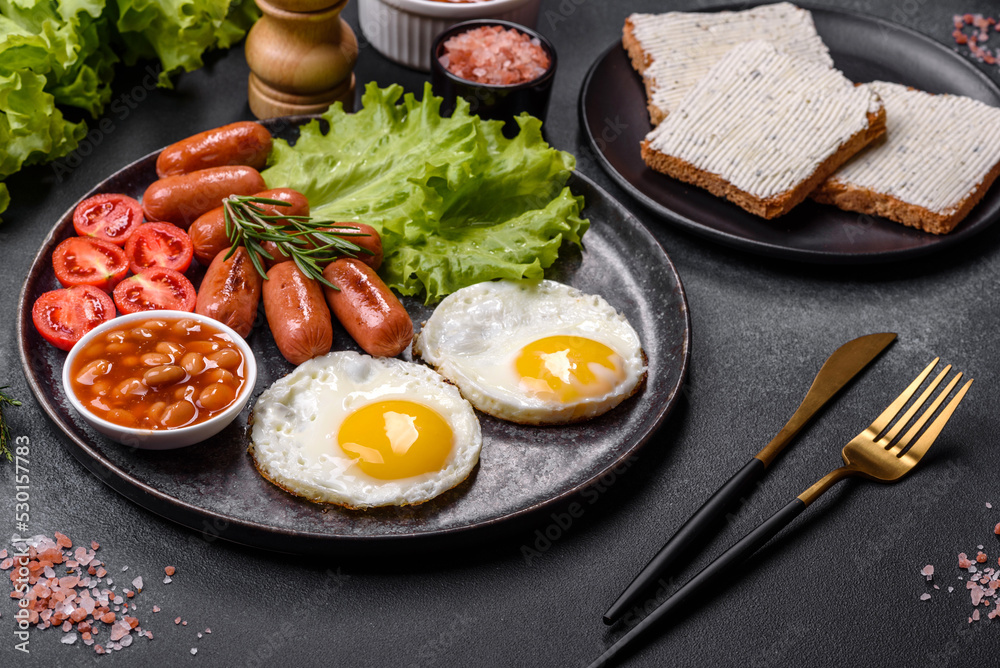 Traditional English breakfast with eggs, toast, sausages, beans, spices and herbs on a grey ceramic plate