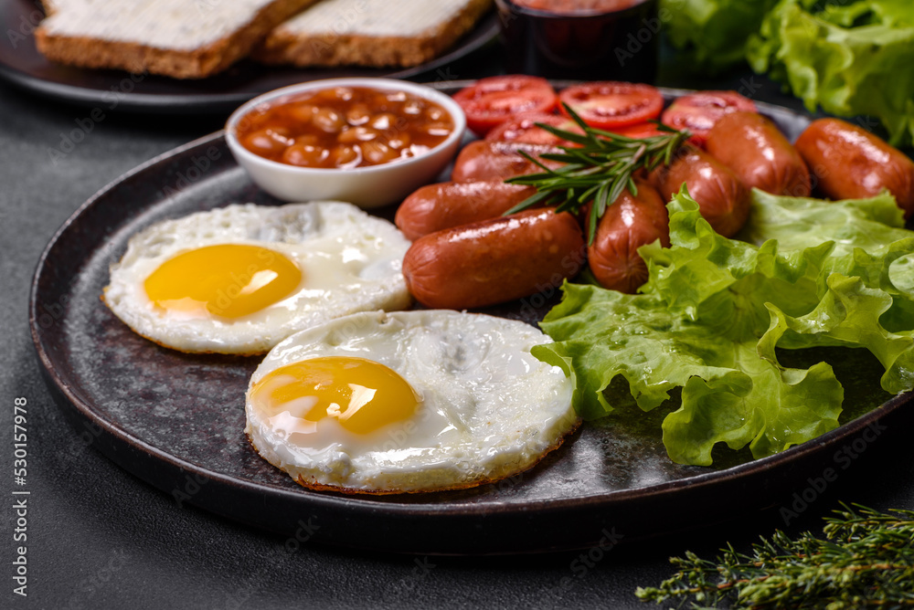 Traditional English breakfast with eggs, toast, sausages, beans, spices and herbs on a grey ceramic plate Traditional English breakfast with eggs, toast, sausages, beans, spices and herbs on a grey ceramic plate