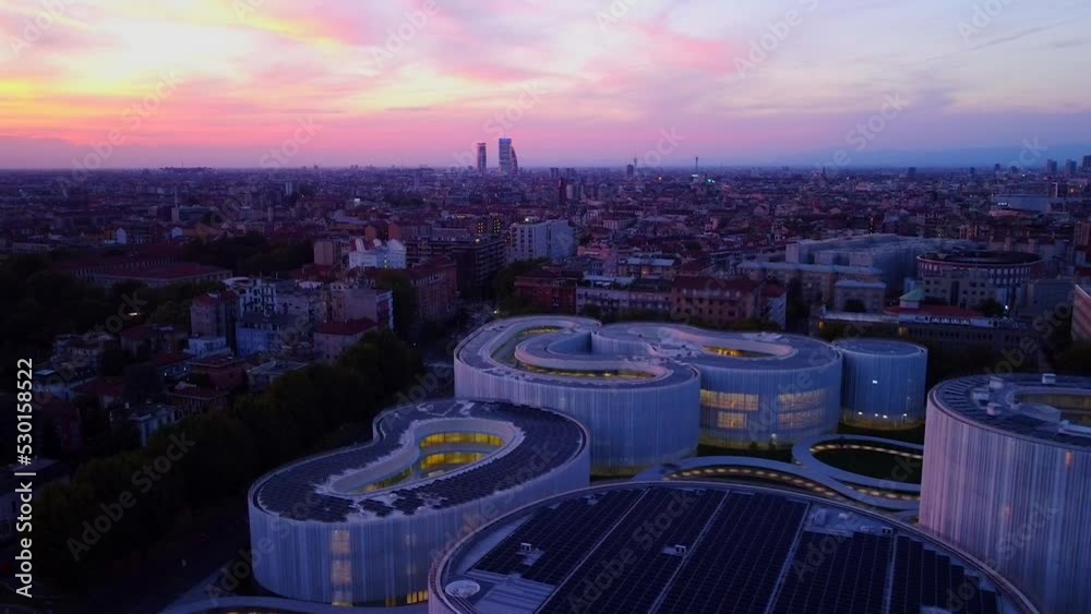 Aerial view of solar panels on the roof. The new campus of the SDA Bocconi School of Management is a modern building with classrooms. Colorful sky at sunset. Ecological energy. Milan Italy 09:2022