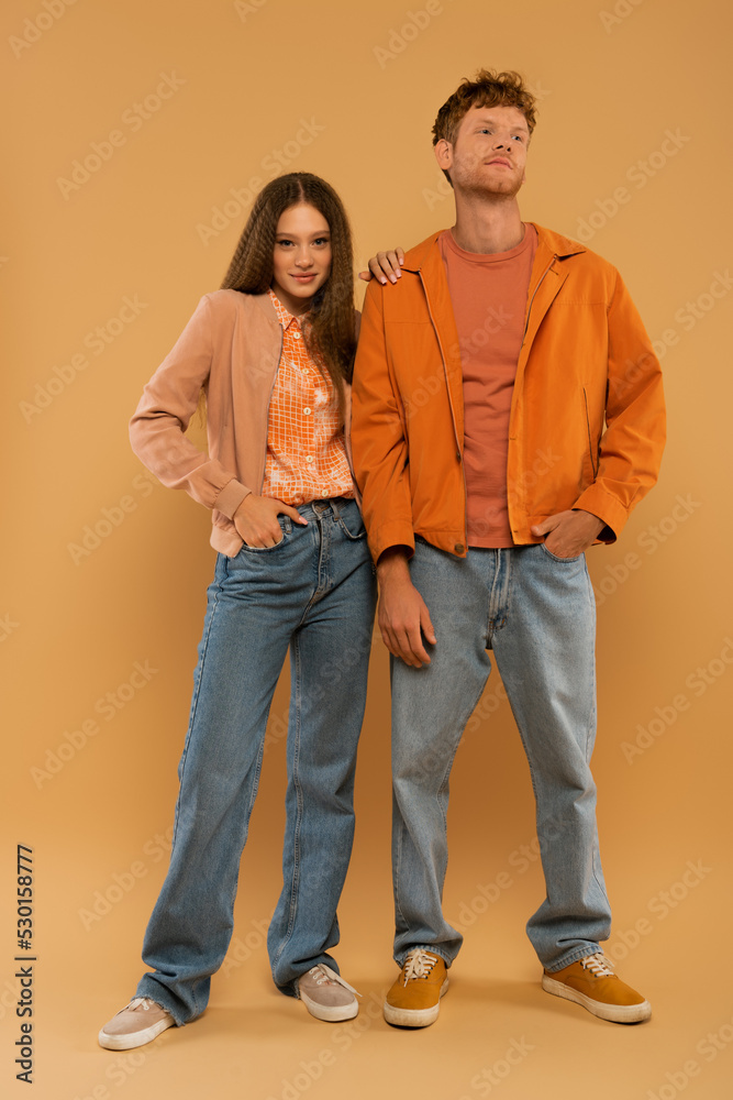 full length of happy young couple in autumnal outfits and gumshoes posing together on beige. full length of happy young couple in autumnal outfits and gumshoes posing together on beige.