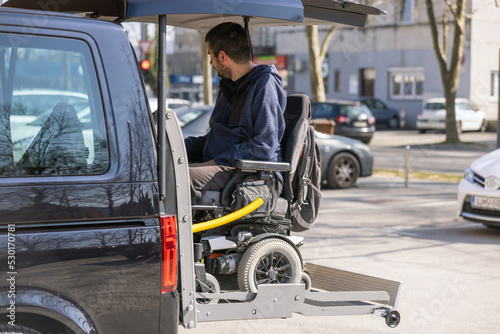 Man with disability using hydraulic wheelchair lift to get in the van, after a summer day spent on beautiful mountain nature © 24K-Production