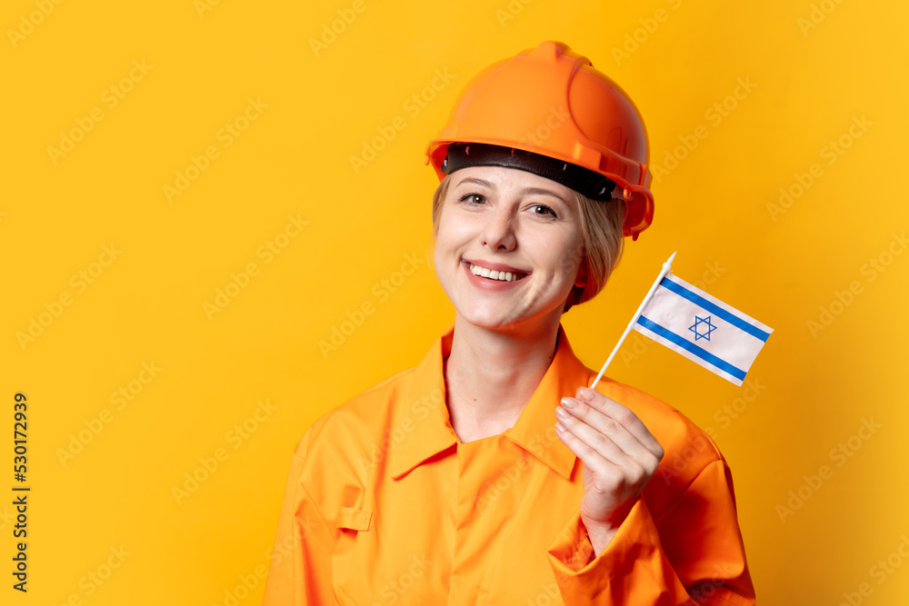 woman worker in helmet and orange overalls holding Israel flag woman worker in helmet and orange overalls holding Israel flag