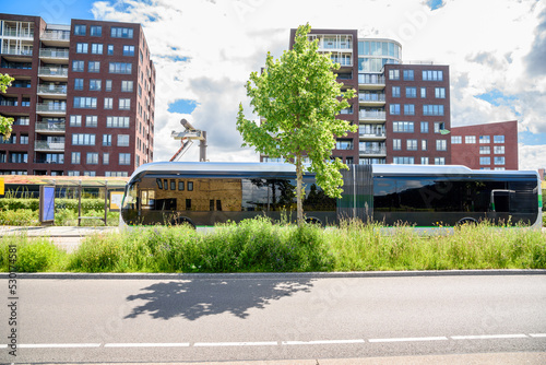 Electric city bus being recharged at a bus stop in a suburban residential district