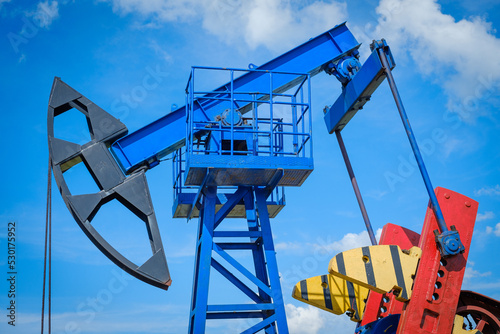 Oil derricks against cloudy sky photo