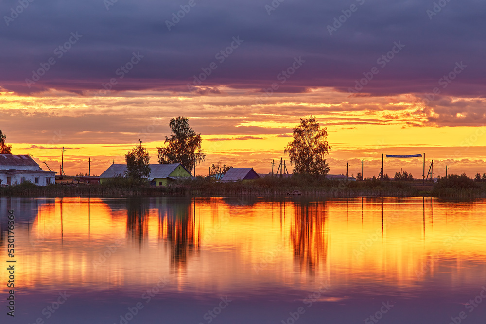 Summer sunset on Lake. Natural rural landscape, autumn September evening. Village on lakeside. Dusk rural scene. Storm cloudscape