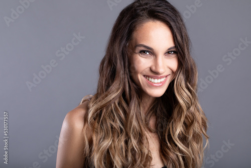Close up of a beautiful smiling young woman look at camera isolated on gray