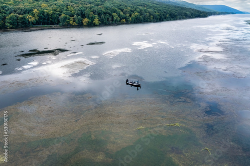 Man fishing in a bass boat surrounded by grass and milfoil on Lake Guntersville in Scottsboro Alabama. photo