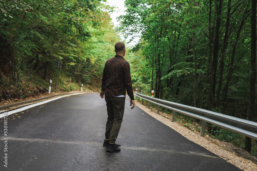 a young man is walking near the road and in the forest a young man is walking near the road and in the forest