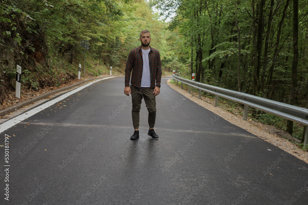 a young man is walking near the road and in the forest a young man is walking near the road and in the forest