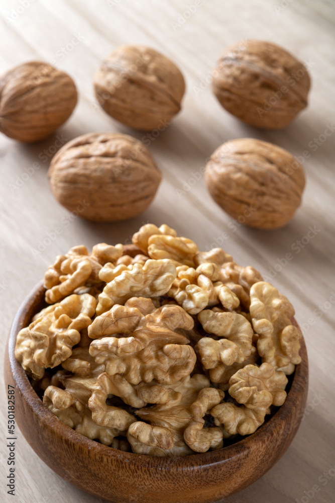 Peeled walnuts and whole walnuts in wooden bowl Peeled walnuts and whole walnuts in wooden bowl