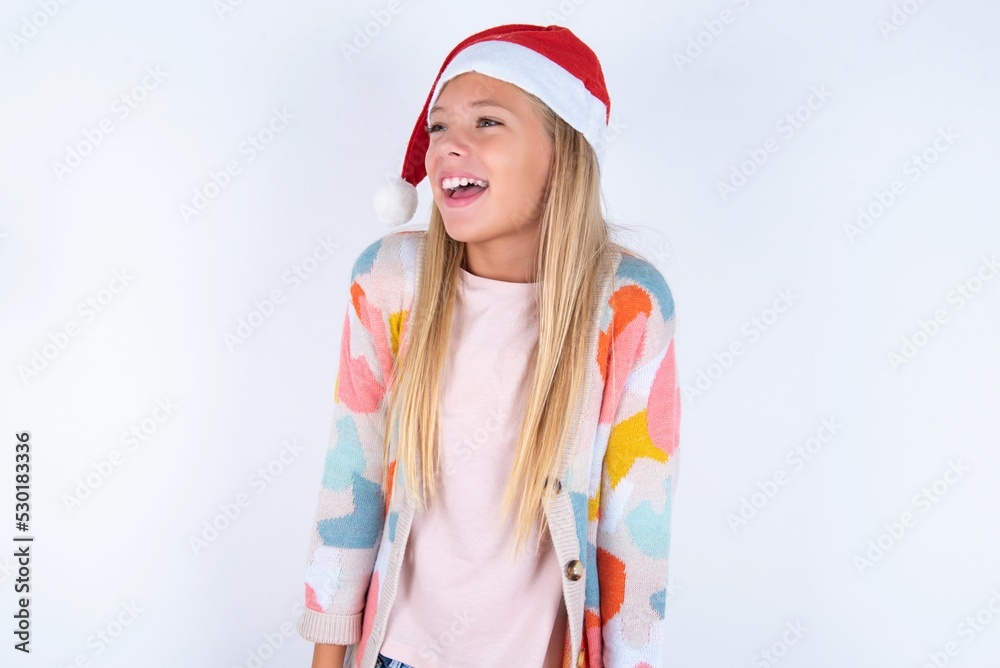 little kid girl with Christmas hat wearing yarn jacket over white background very happy and excited about new plans. little kid girl with Christmas hat wearing yarn jacket over white background very happy and excited about new plans.