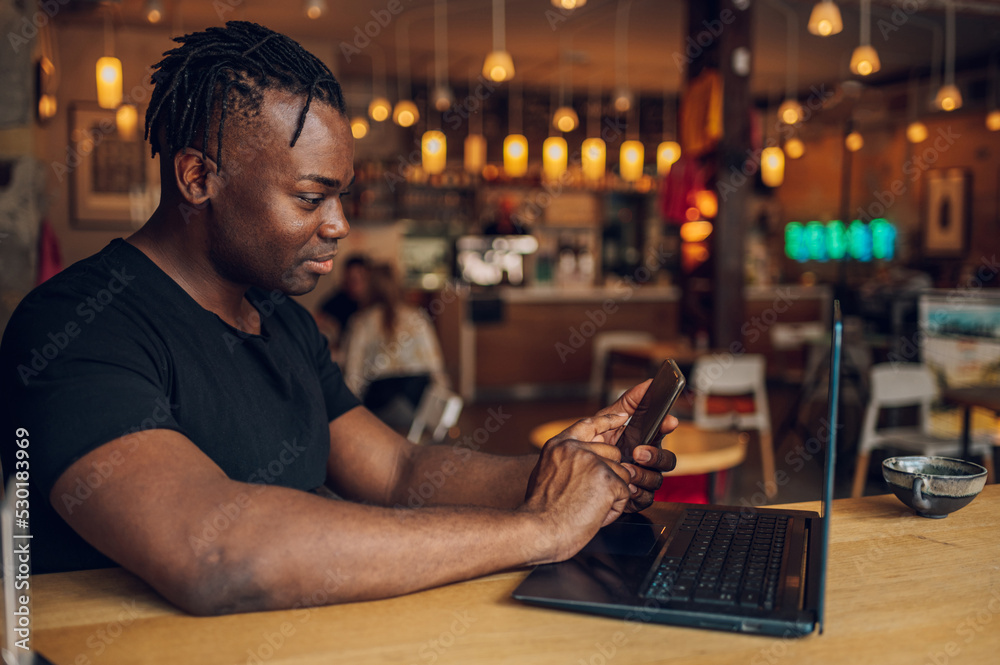 African american man using laptop while drinking coffee in a cafe African american man using laptop while drinking coffee in a cafe