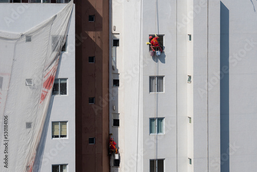 Trabalhadores da construção civil fazendo manutenção predial por meio de rapel photo