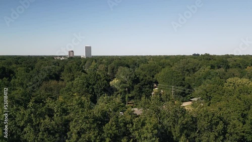 Drone flying around suburb neighborhoods with city skyscrapers in the background.