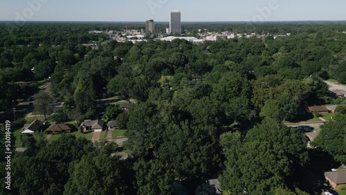 Drone flying around suburb neighborhoods with city skyscrapers in the background.
