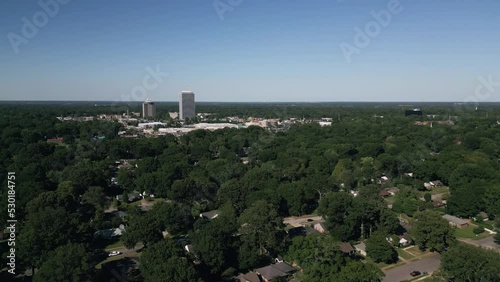 Drone flying around suburb neighborhoods with city skyscrapers in the background.