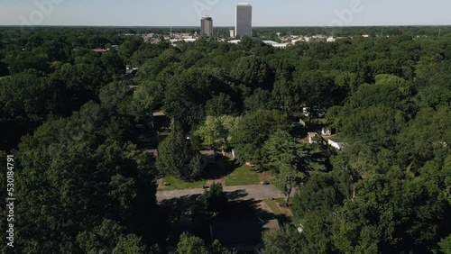 Drone flying around suburb neighborhoods with city skyscrapers in the background.