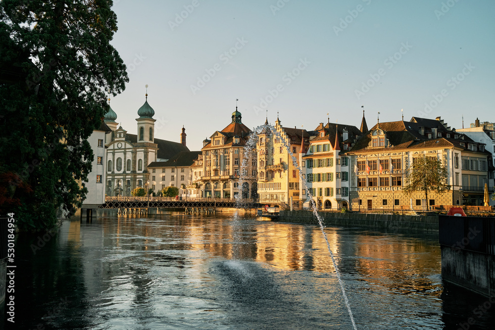 Water jet flowing into river at sunset in Lucerne Water jet flowing into river at sunset in Lucerne