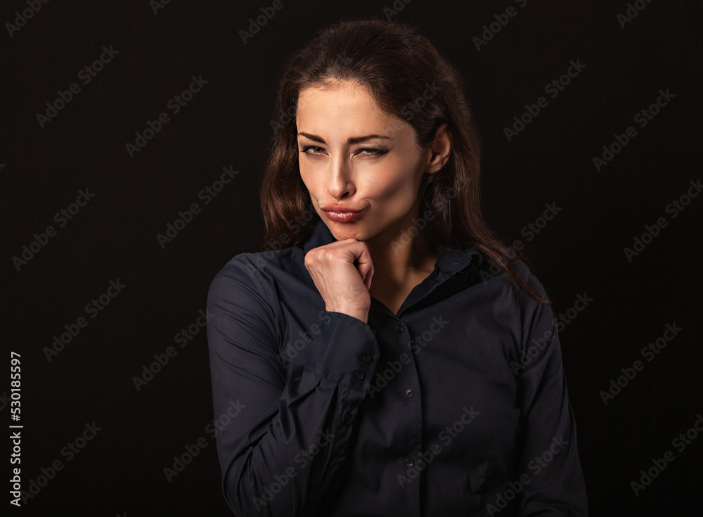 Beautiful thinking grimacing fun business woman with folded arms in blue shirt on black background with empty copy space for text. Closeup Beautiful thinking grimacing fun business woman with folded arms in blue shirt on black background with empty copy space for text. Closeup