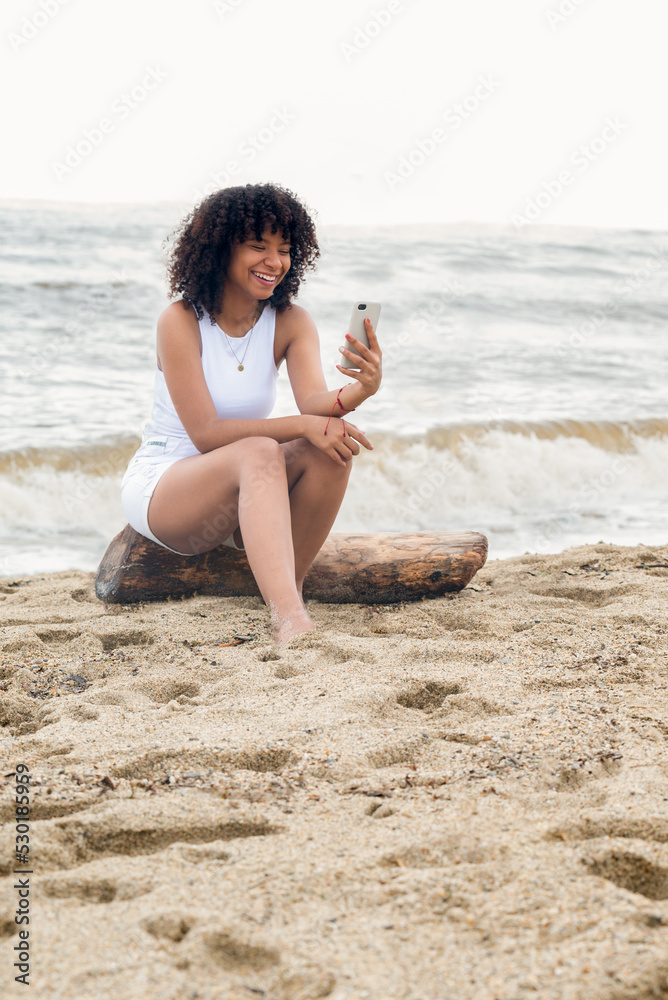 Smiling african american woman taken a video call on the beach Smiling african american woman taken a video call on the beach