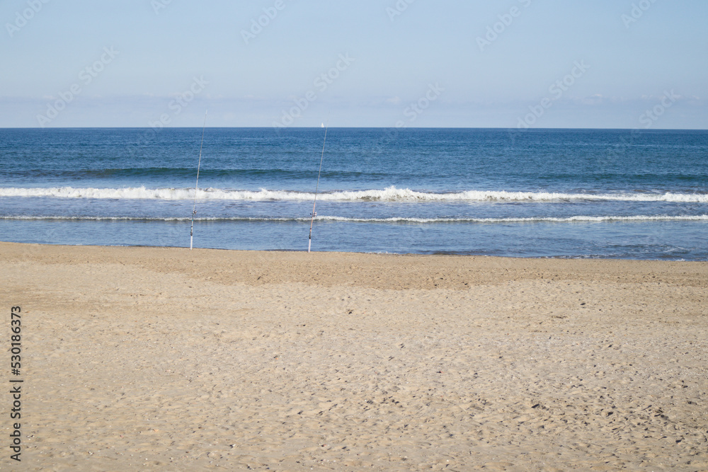 Landscape of a beach facing the sea where some fishermen have left their fishing rods