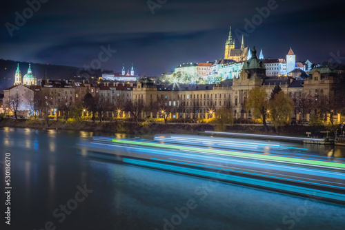 Hradcany, St Vitus Cathedral and Vltava river at night with blurred boat, Prague