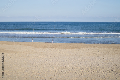 Landscape of a beach facing the sea where some fishermen have left their fishing rods