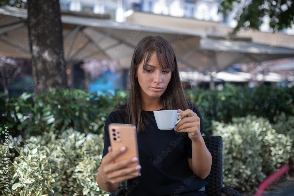 Morning in cafe - attractive woman in black drinkin coffe and make selfie photo for social networks Morning in cafe - attractive woman in black drinkin coffe and make selfie photo for social networks